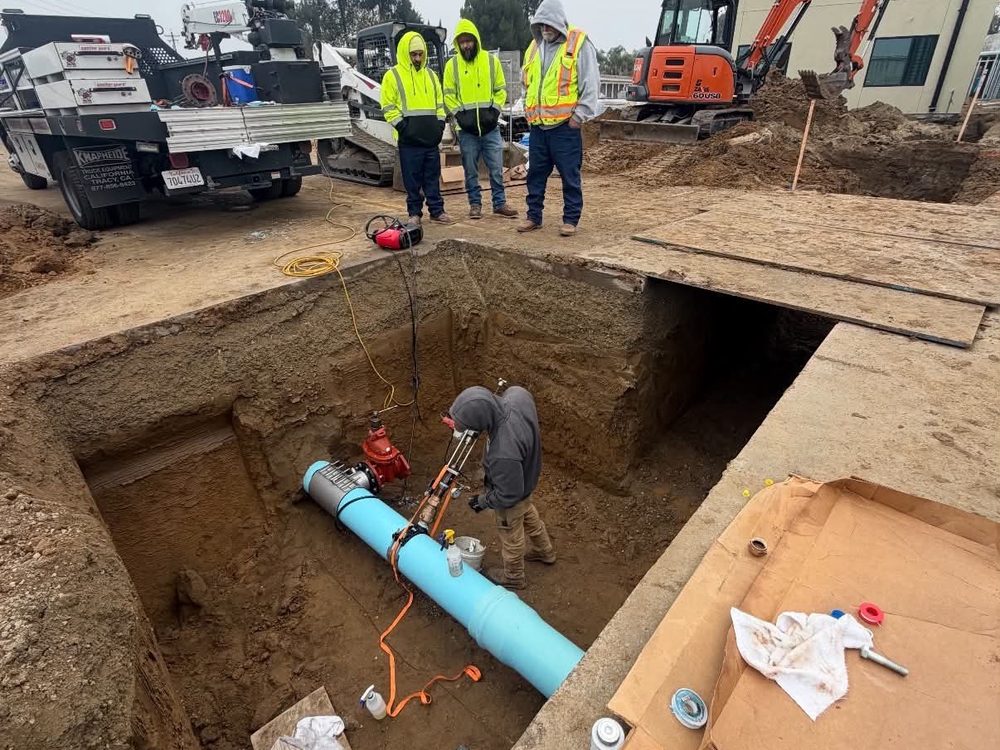 Crew working an open excavation alongside an excavator