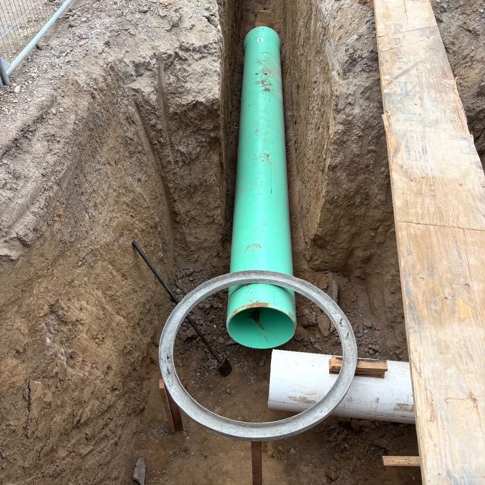 Sewer pipe set through a manhole collar in a shored trench